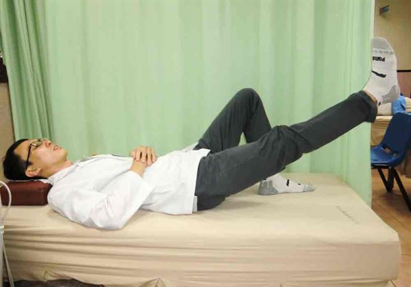 【直膝抬腿運動】：藉由健側腳彎曲踩床。(圖片提供／活力得中山脊椎外科醫院)