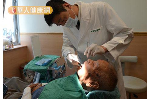 醫師許博智（站立）替高齡92歲的蘇姓老翁（躺）檢查口腔。（圖片提供／台北慈濟醫院）